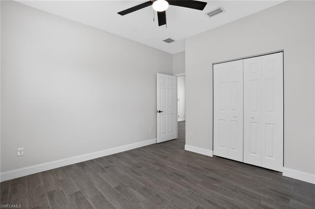 Wood-finish flooring with white trim, bi-fold closet doors, a modern ceiling fan, and light gray wall paint