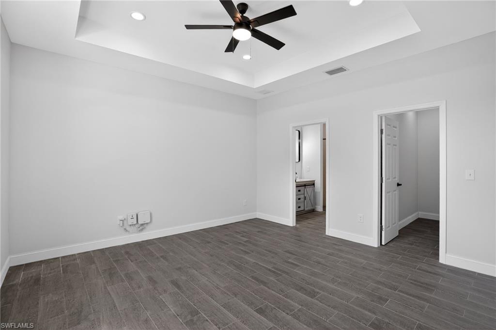 Recessed lighting, ceiling fan, tray ceiling, wood-finish flooring, and white interior doors