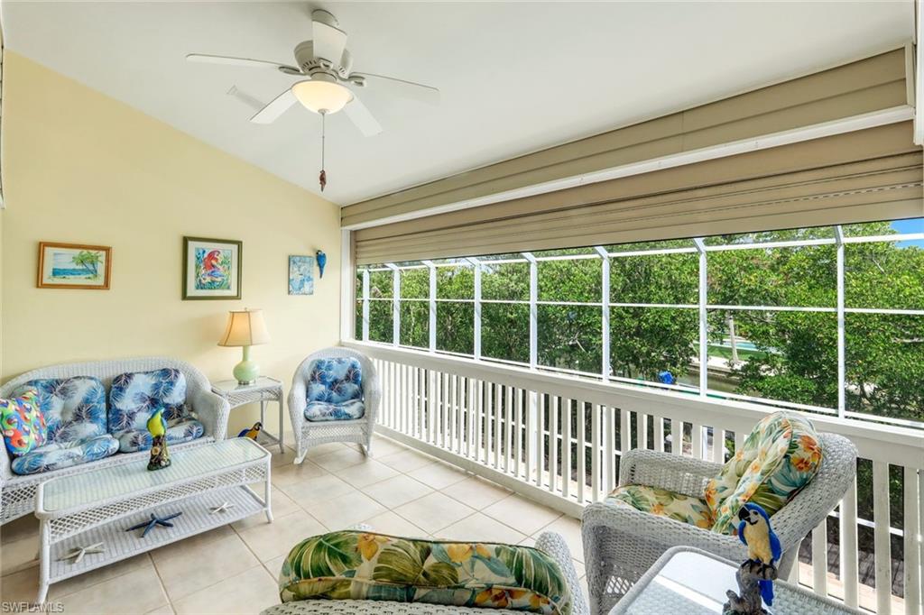 Screened-in porch featuring a vaulted ceiling with a ceiling fan, light-toned tile flooring, and exterior roll-down shades