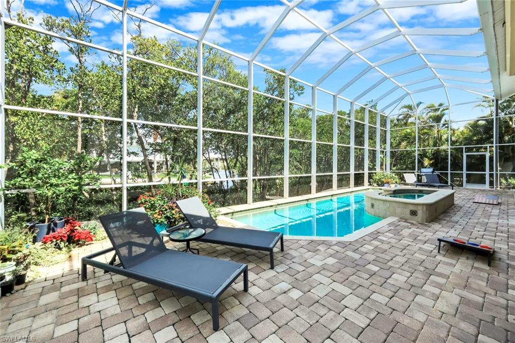 Screened outdoor living space featuring a swimming pool, integrated spa, and extensive paver patio