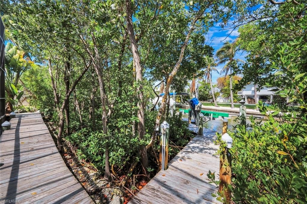 Wooden dock with integrated lighting, lush tropical foliage, and tranquil canal access