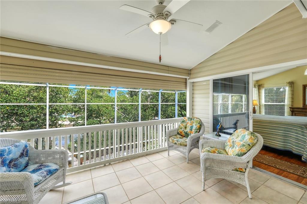 Screened balcony featuring a ceiling fan with integrated lighting, tile flooring, and a sliding glass door