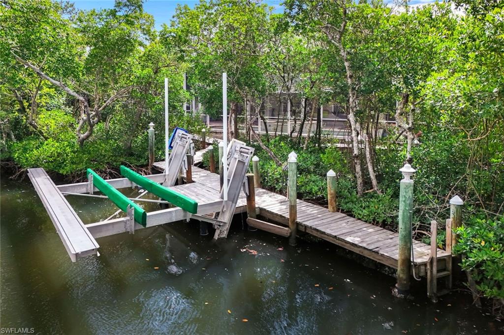 Private dock featuring a boat lift, wooden planks, and integrated lighting on piling caps