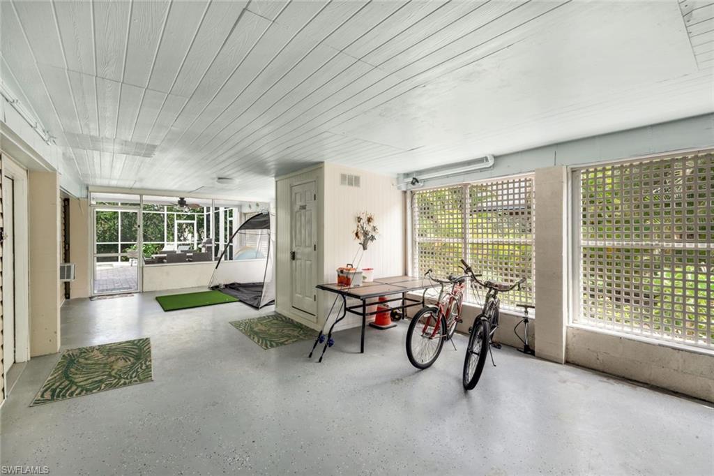 Screened enclosure with expansive lattice windows, beadboard ceiling, and concrete flooring