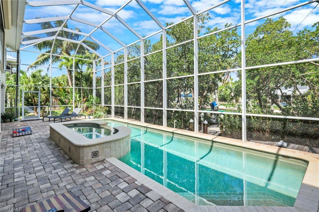 Screened outdoor living area featuring a swimming pool, integrated spa, and paver patio