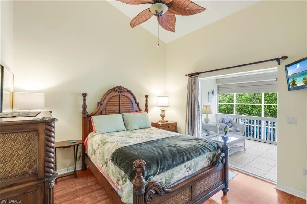 Vaulted ceiling with an integrated ceiling fan, wood-finish flooring, and direct access to a private tiled balcony with a white railing