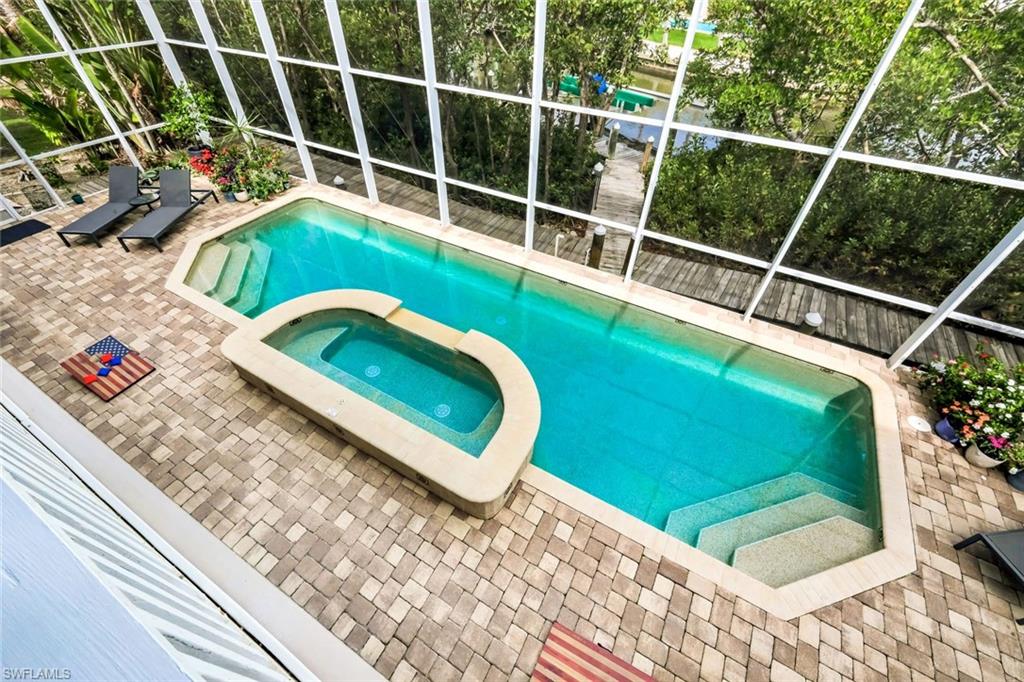 Screened outdoor living area featuring a custom-shaped pool and integrated spa