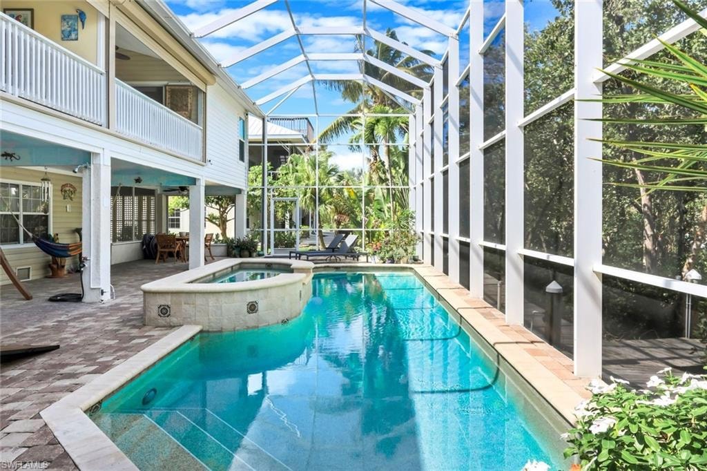 Screened enclosure featuring a swimming pool, integrated spa, and paver patio
