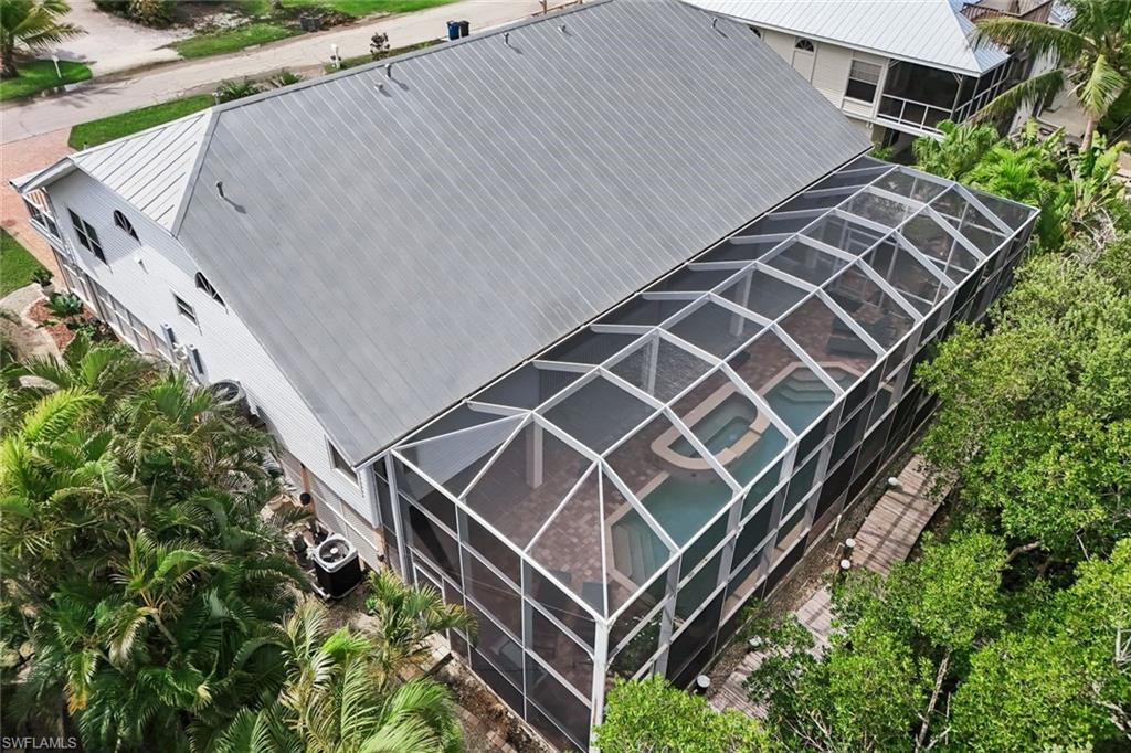 Metal roof, screened pool enclosure, curved pool, integrated spa, mature trees