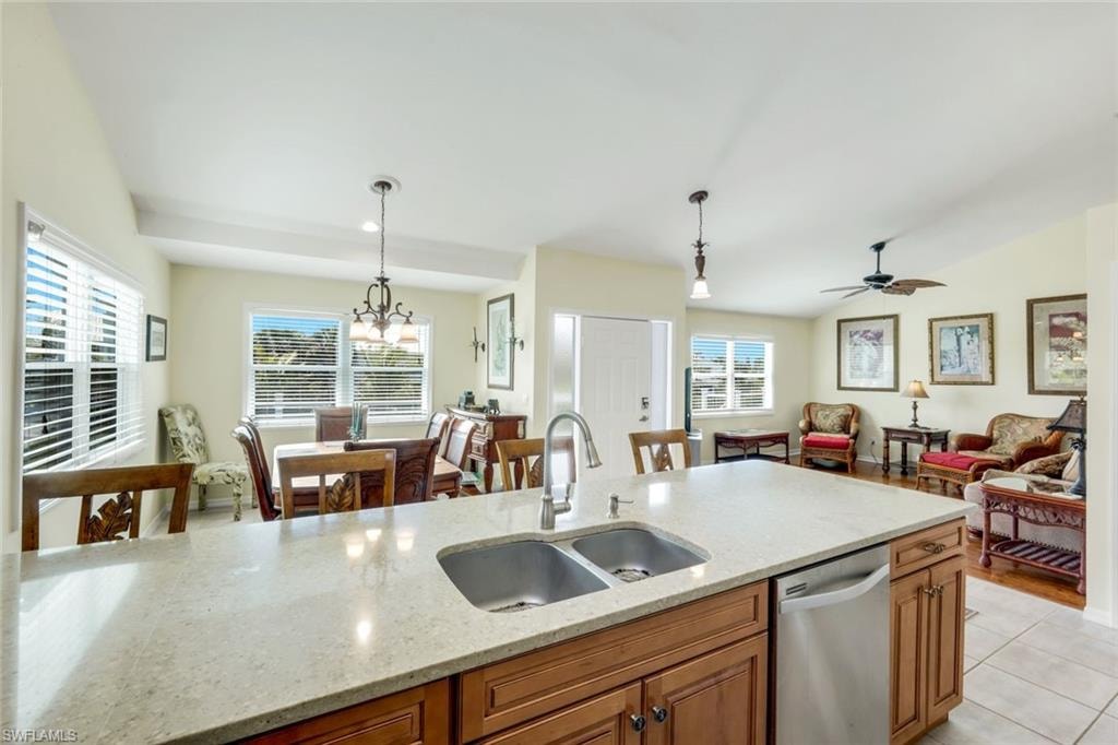 Kitchen island with double basin sink, light-toned countertop, and wood-finish cabinetry