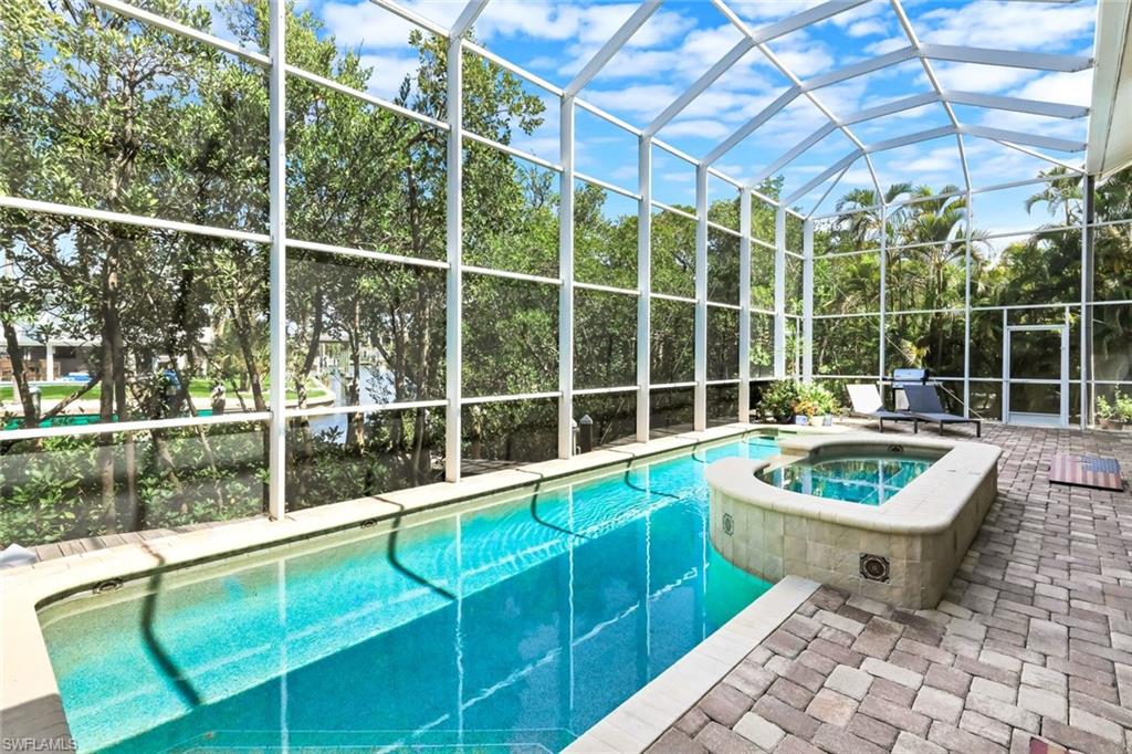 Screened pool enclosure featuring a pool and integrated spa