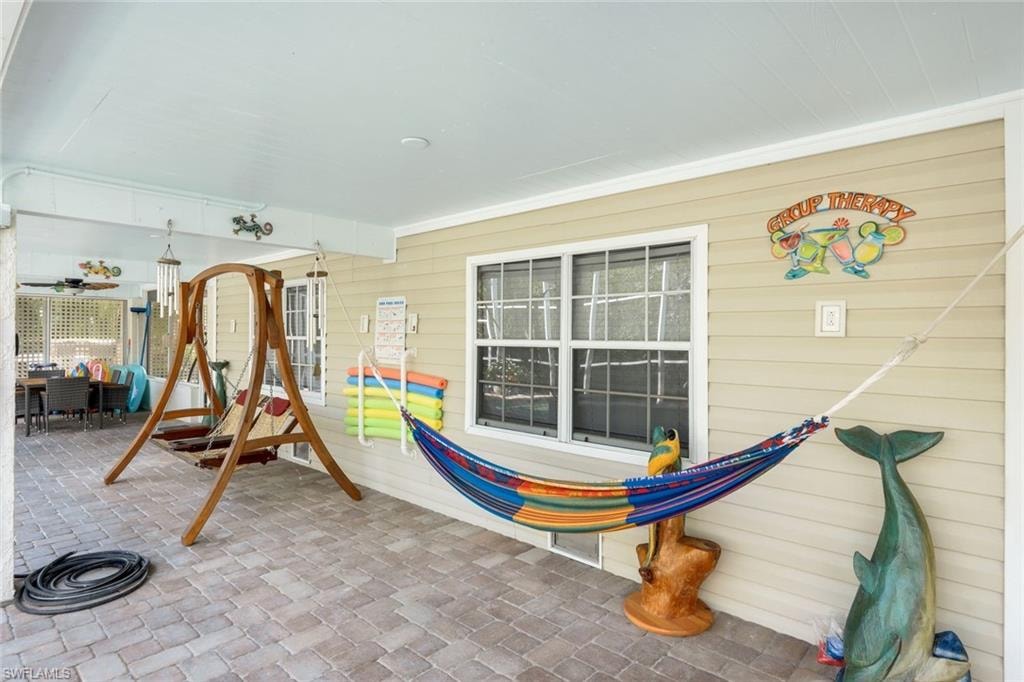 Covered patio featuring a paver stone floor, wood-finish porch swing, and a built-in ceiling fan