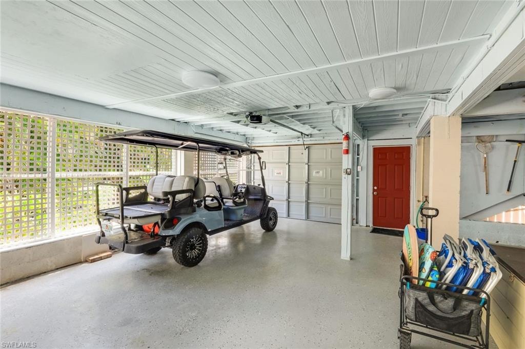 Covered parking area with an epoxy-coated concrete floor, white lattice screening, and a red entry door