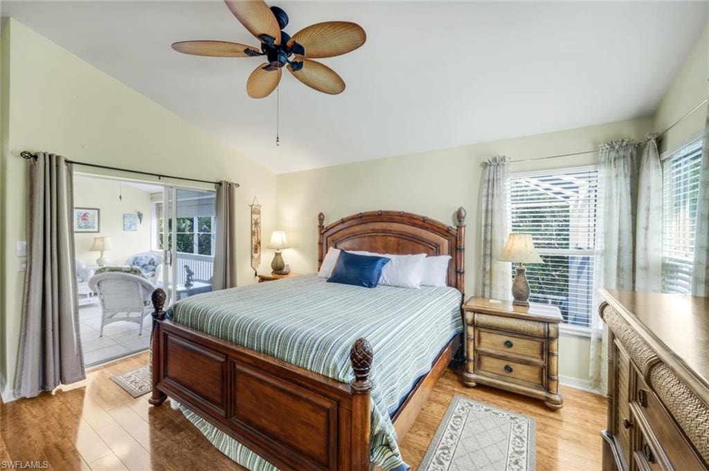 Vaulted ceiling featuring a ceiling fan, wood-finish flooring, and sliding glass doors to the exterior