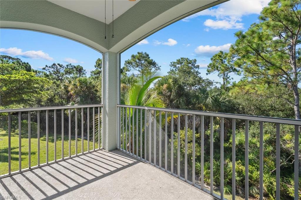 Spacious covered balcony with a concrete floor, metal railing, and a ceiling fan