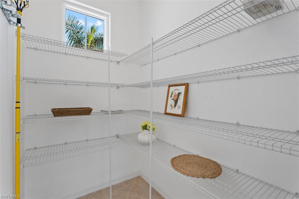 Walk-in pantry with wire shelving, a rectangular window, and neutral-toned floor tile