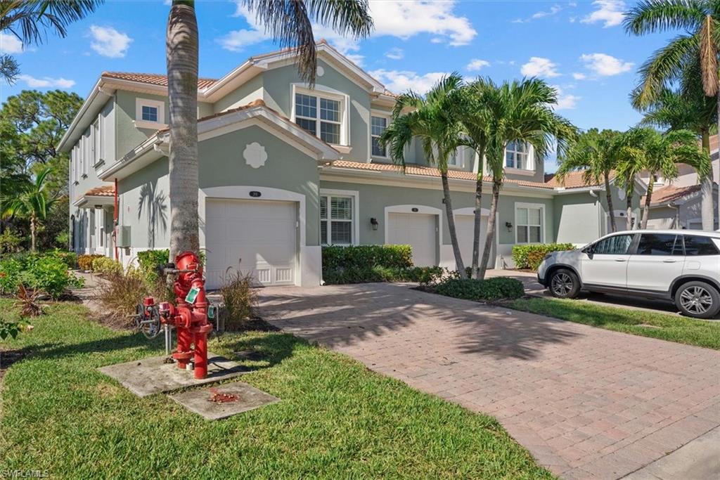 Stucco exterior with a tile roof, integrated garage, and a paver driveway