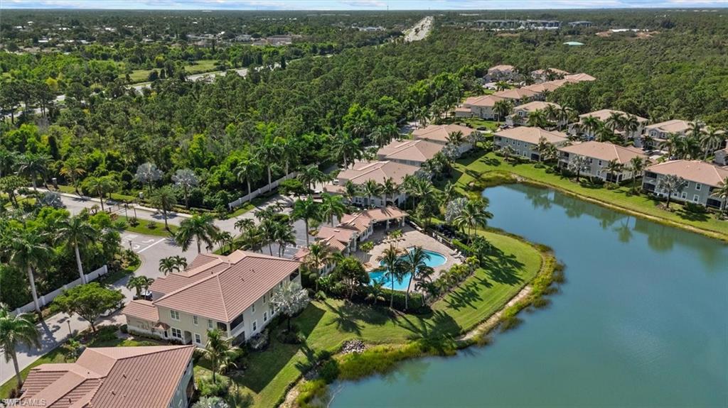 Aerial perspective showcasing a residential community with multiple buildings, a central water feature, and extensive green landscaping