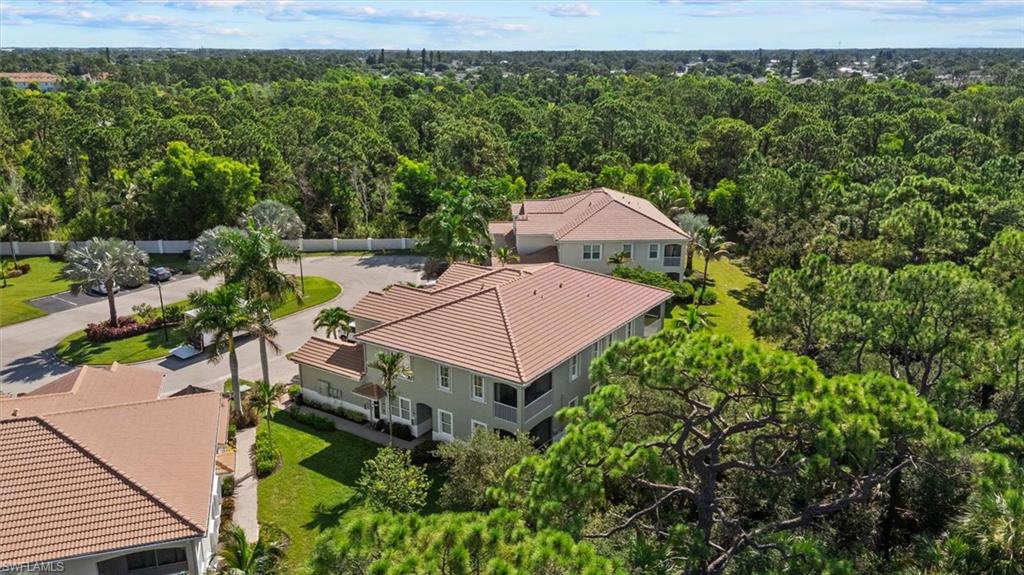 Tile roof, mature trees, manicured lawn, paved parking areas, and a lush, expansive landscape