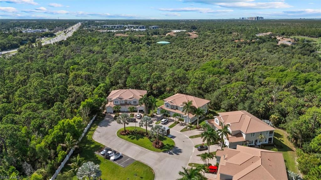 Residential structures with tile roofing, surrounded by extensive mature trees and a paved access road