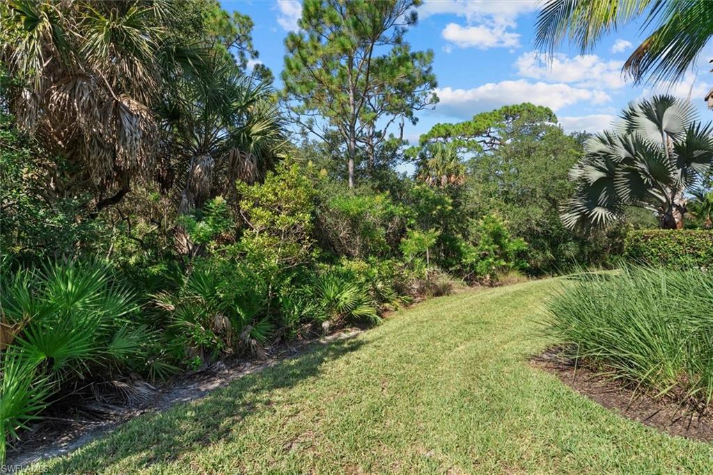 Lush landscaping with mature trees and dense foliage, featuring a manicured lawn and vibrant ground cover