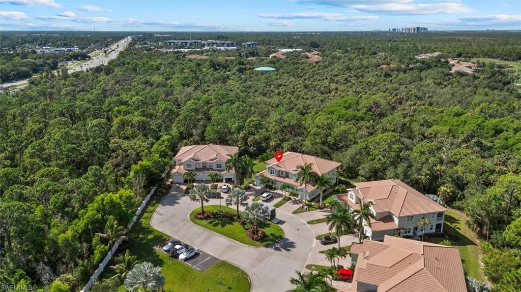 Curved driveway access with ample parking, surrounded by dense natural landscaping
