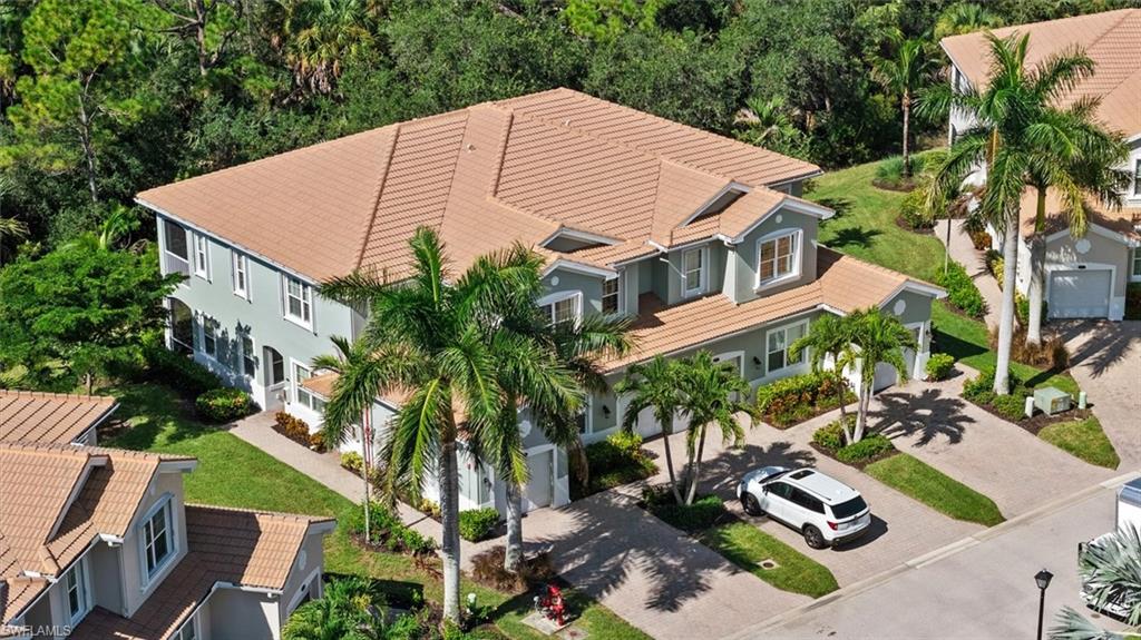 Light blue exterior with tan tile roof, surrounded by mature landscaping and paved driveways