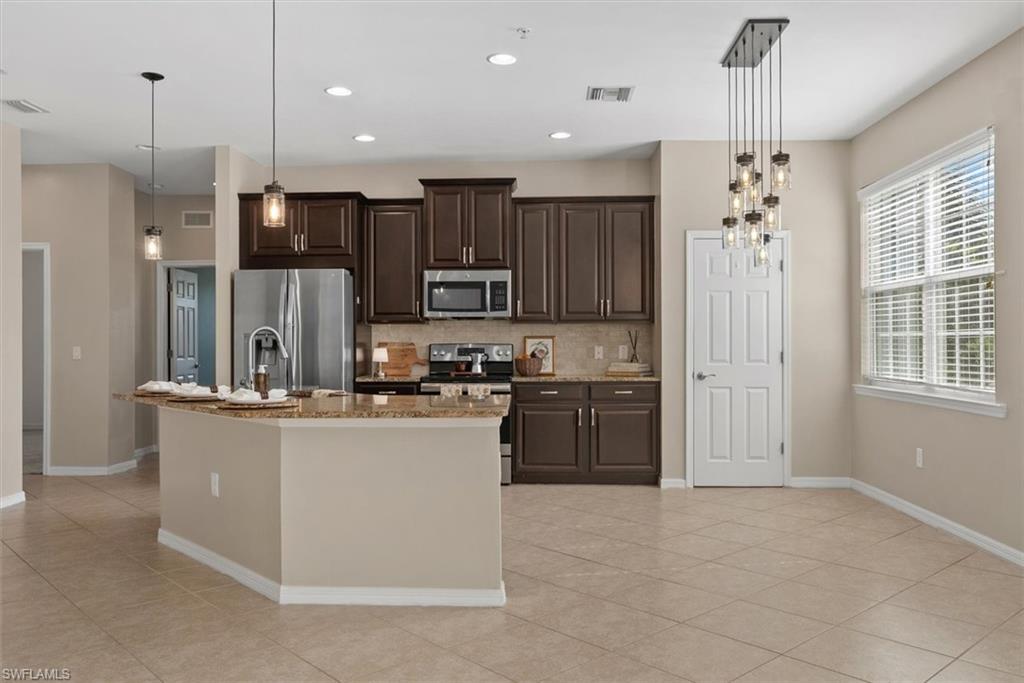 Kitchen with dark wood cabinetry, stainless steel appliances, and a central island with a granite countertop