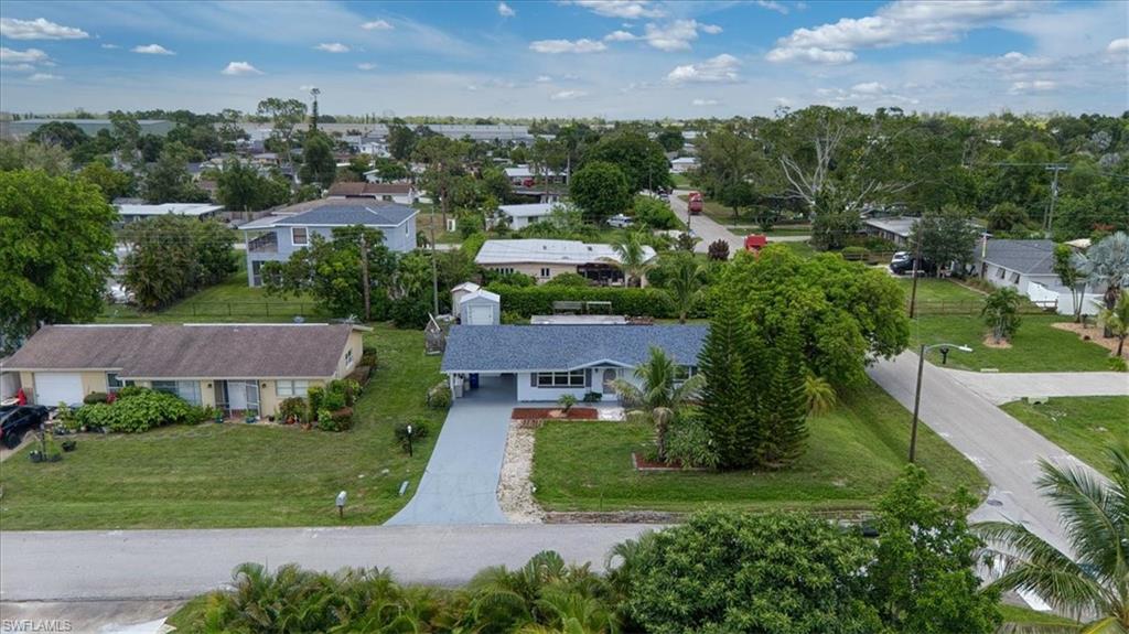 Ranch-style residence featuring a carport, paved driveway, and mature landscaping