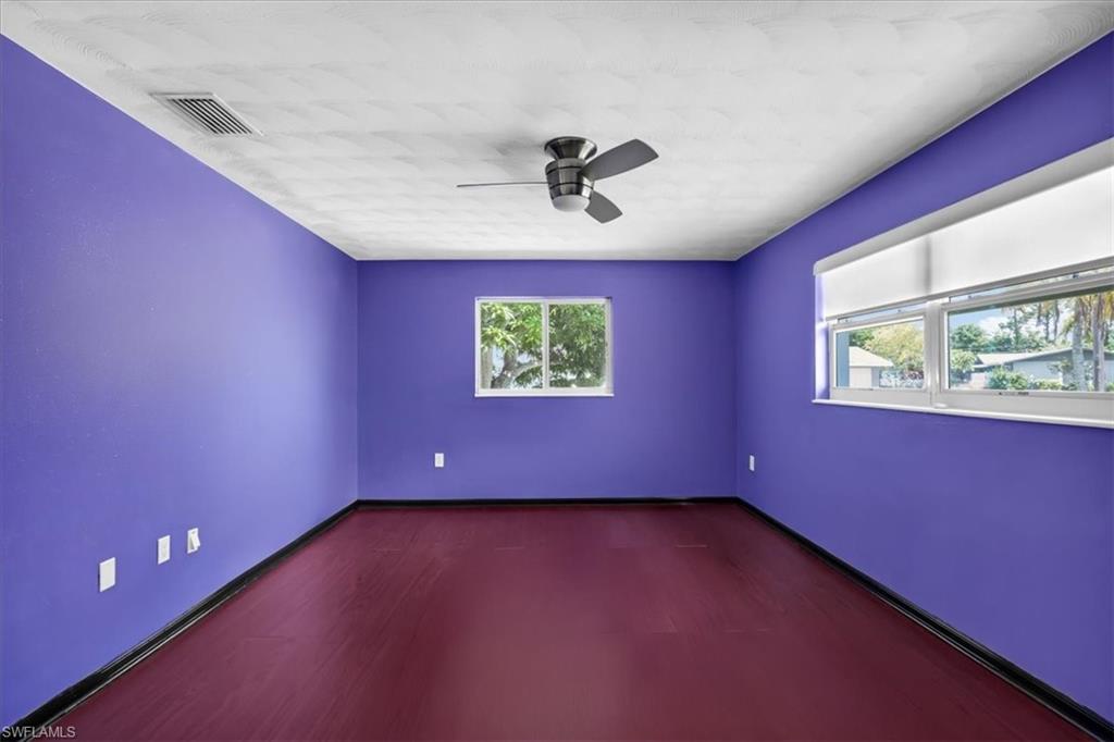 Ceiling fan with light fixture, multiple windows for natural light, and wood-finish flooring
