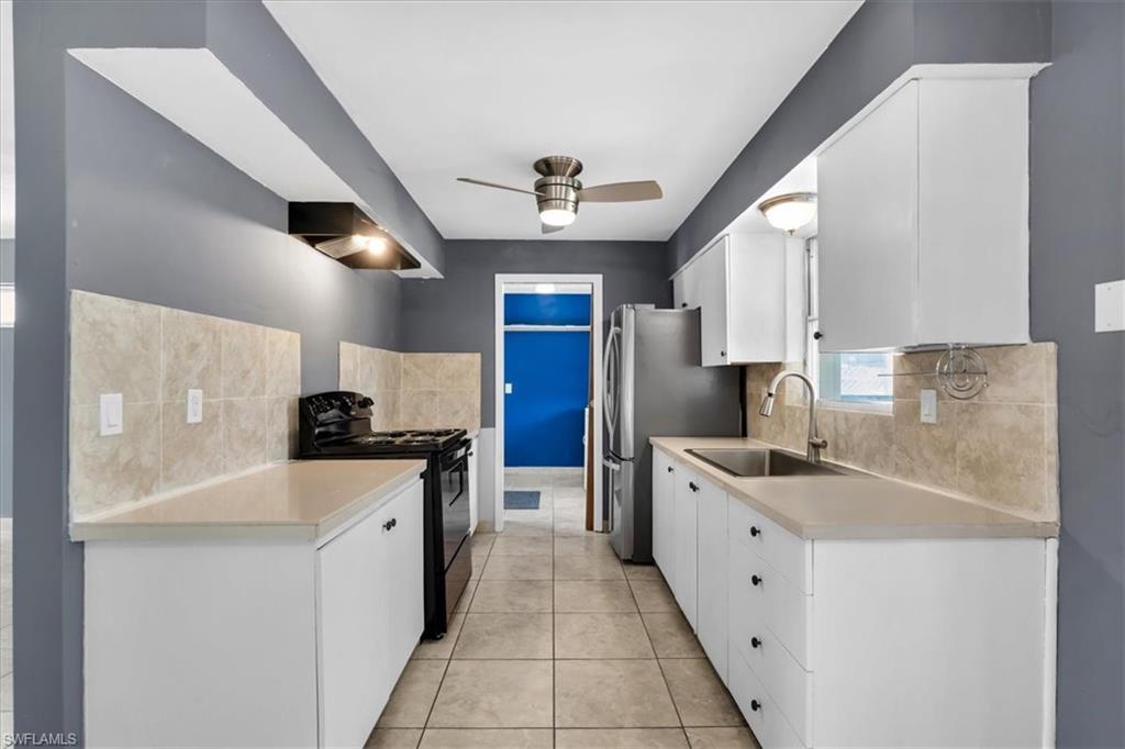 Galley-style kitchen with white cabinetry, light-toned countertops, and a tile backsplash