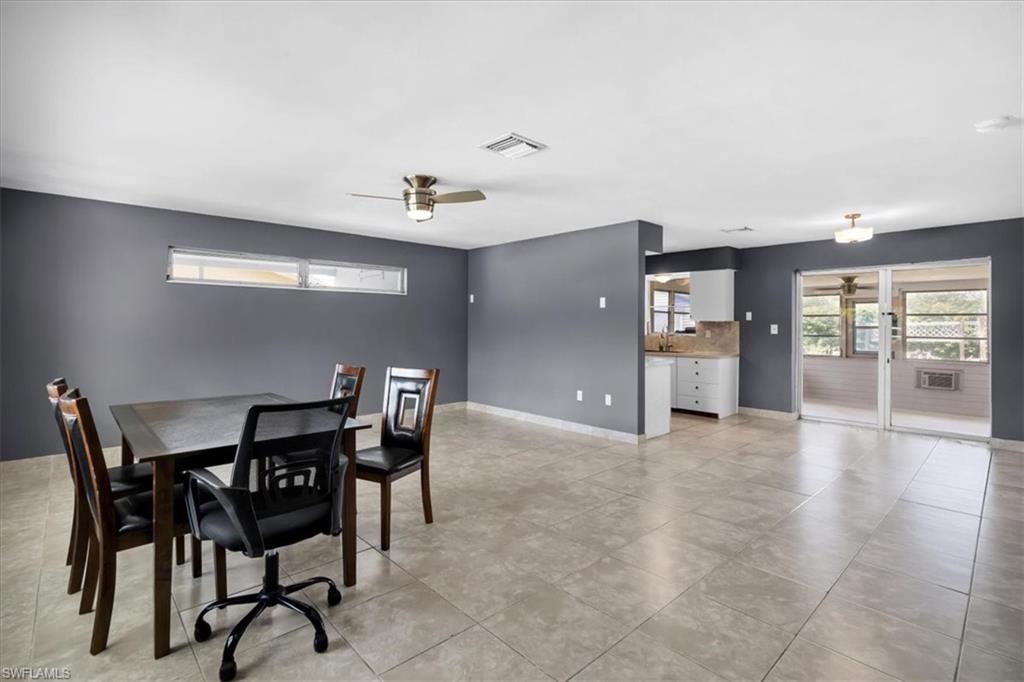 Tile flooring, ceiling fan, transom windows, sliding glass doors, and white cabinetry
