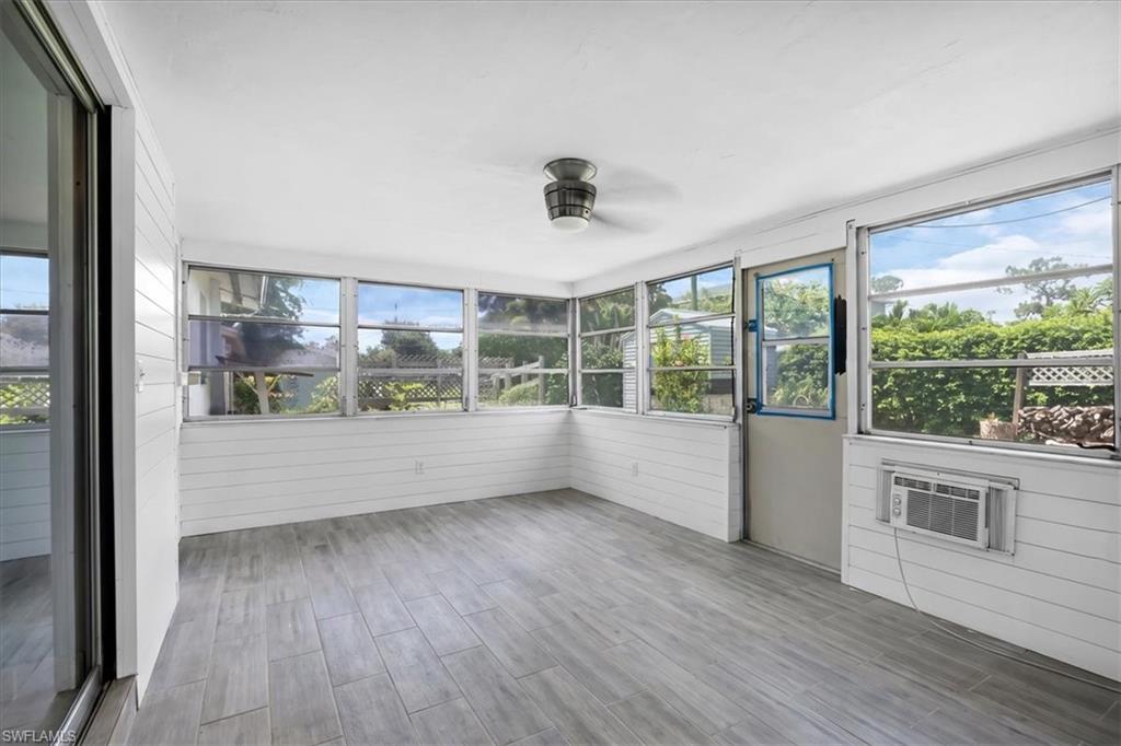 Screened room featuring wood-finish flooring, white horizontal paneling, and multiple windows