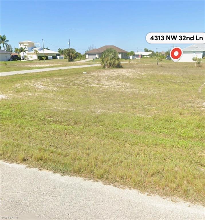 Clear parcel featuring natural grass and distant residential structures