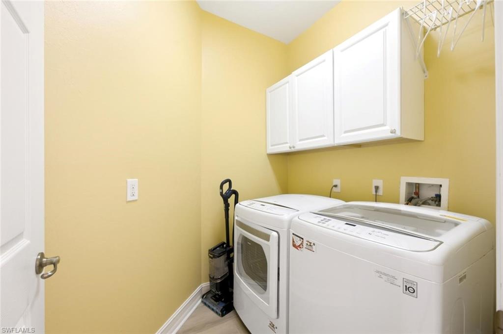 Laundry room featuring white shaker-style cabinetry,  and wood-finish flooring