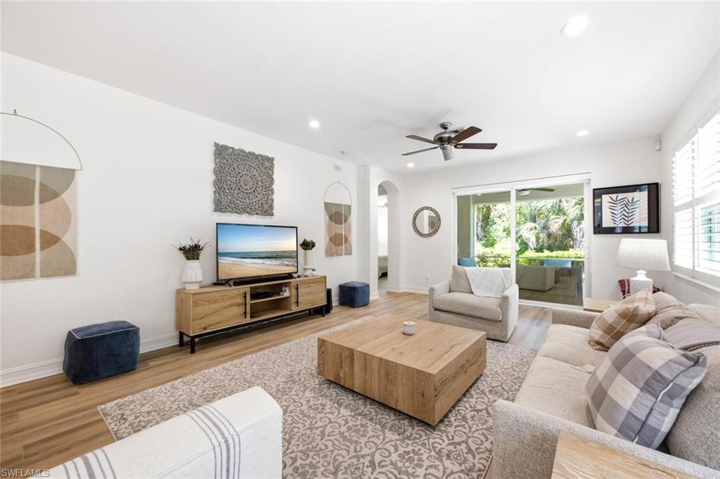 Recessed ceiling lighting, wood-finish flooring, ceiling fan with light, white plantation shutters, and sliding glass impact doors