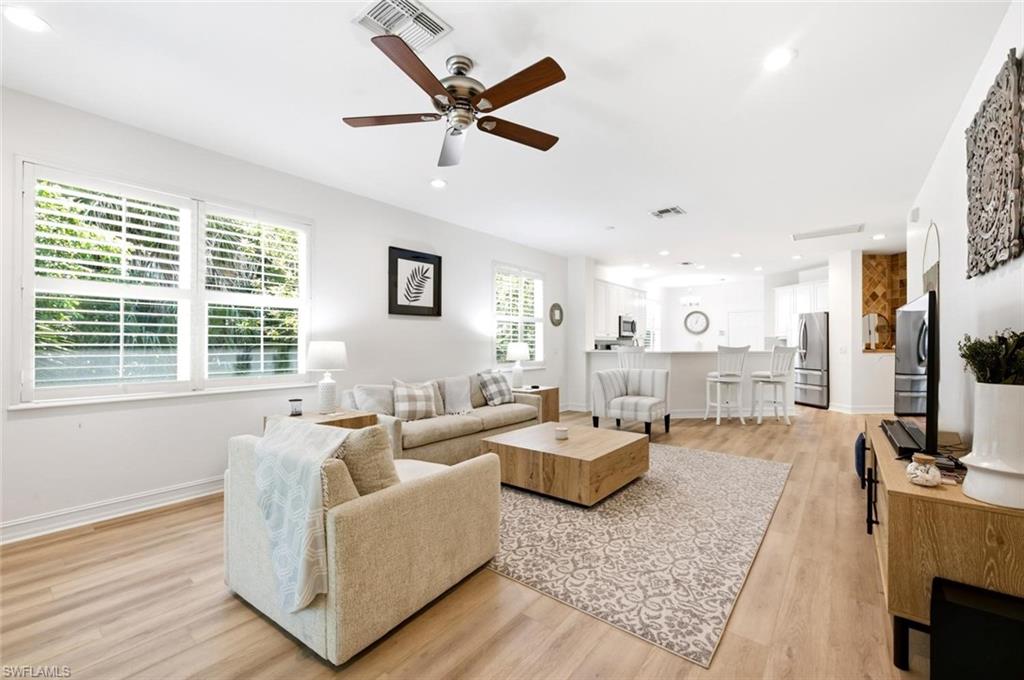 Open-concept living space featuring wood-finish flooring, white plantation shutters, and recessed lighting