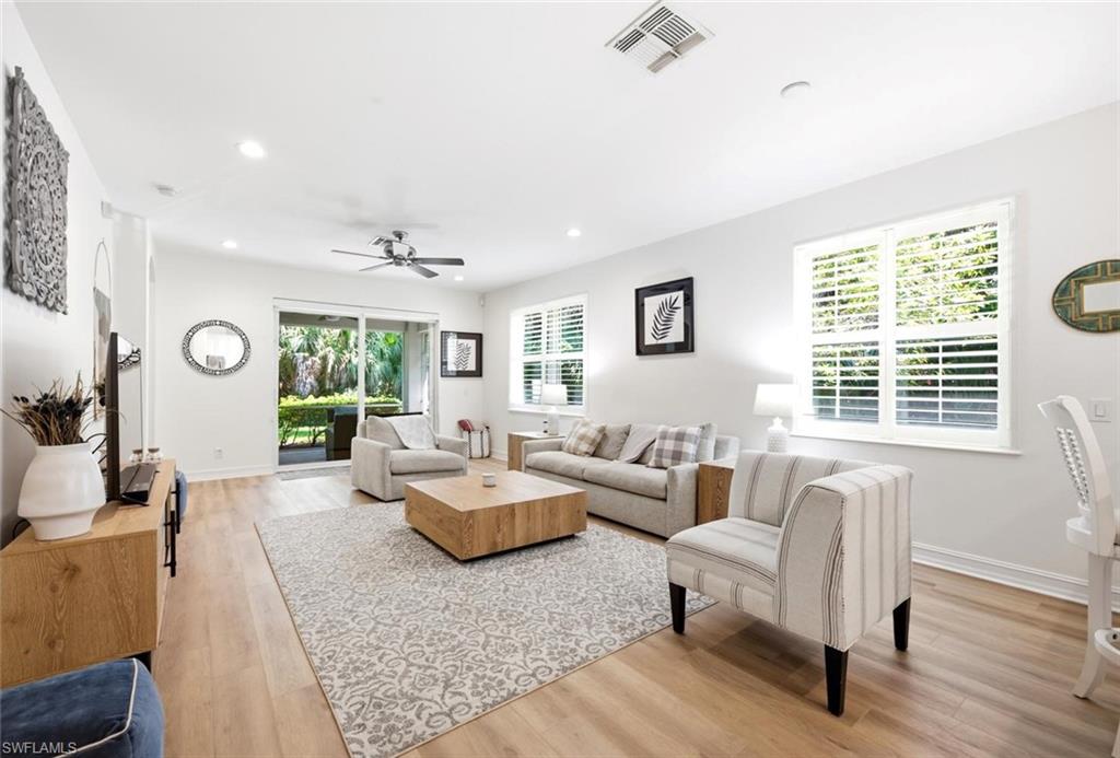 Recessed lighting and ceiling fan, wood-finish flooring, sliding glass impact door, multiple impact windows with white plantation shutters, and light-toned walls