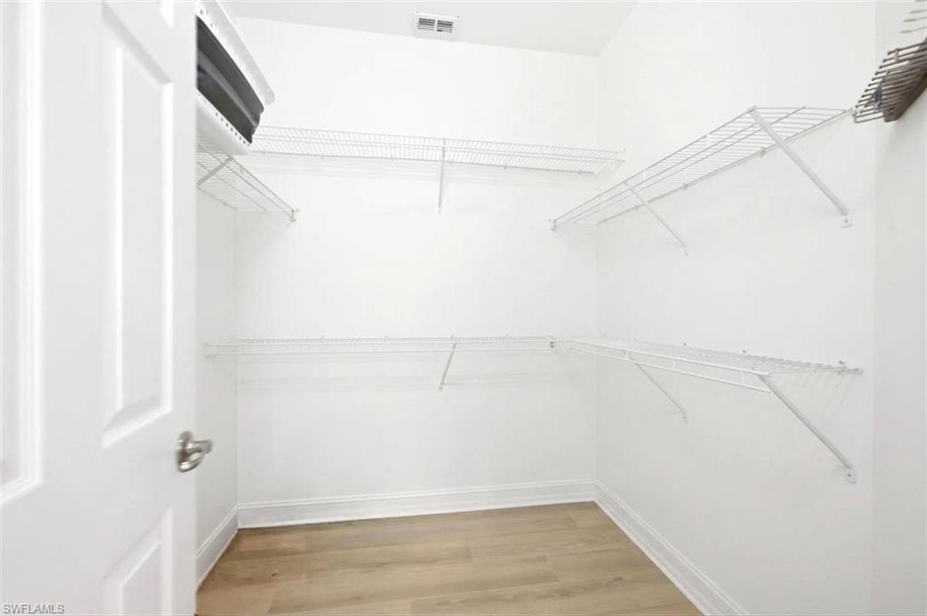 Walk-in closet with wire shelving, light wood-finish flooring, and white trim