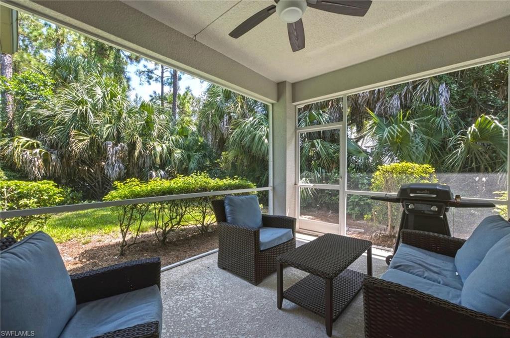 Screened lanai with a concrete surface, overhead ceiling fan, and lush natural landscaping