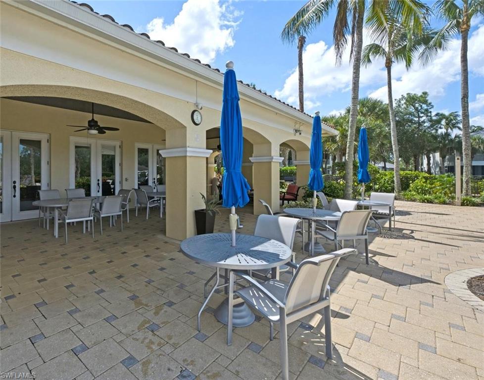 Expansive paver patio with a covered outdoor entertaining area, featuring an arched entryway, ceiling fan, and multiple sets of glass-paneled French doors