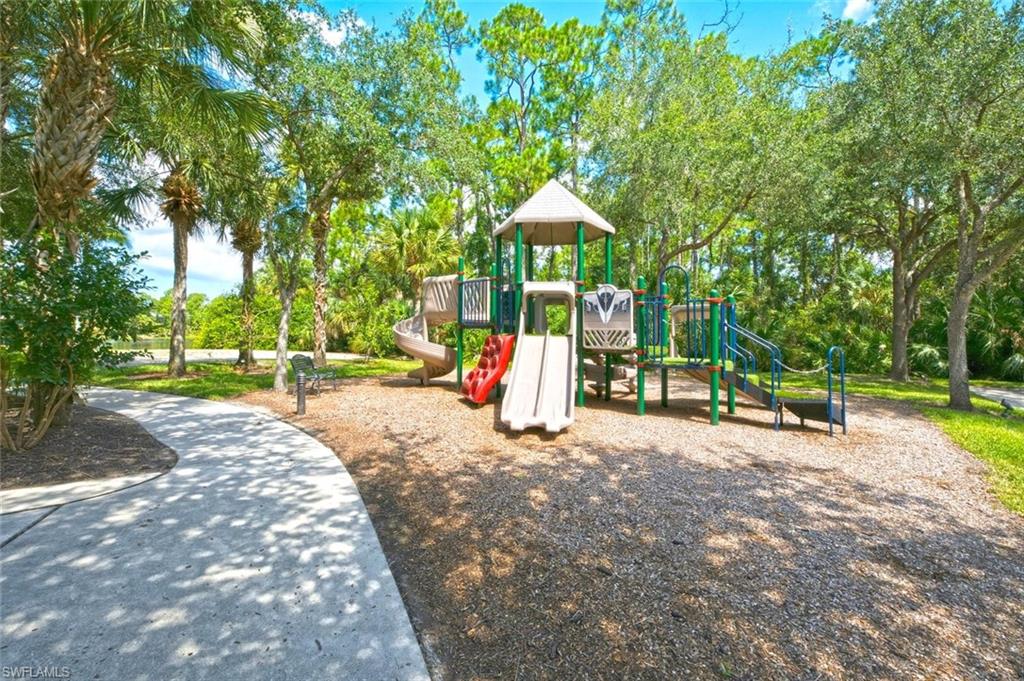Community playground featuring a multi-level play structure, slide, and wood chip ground cover