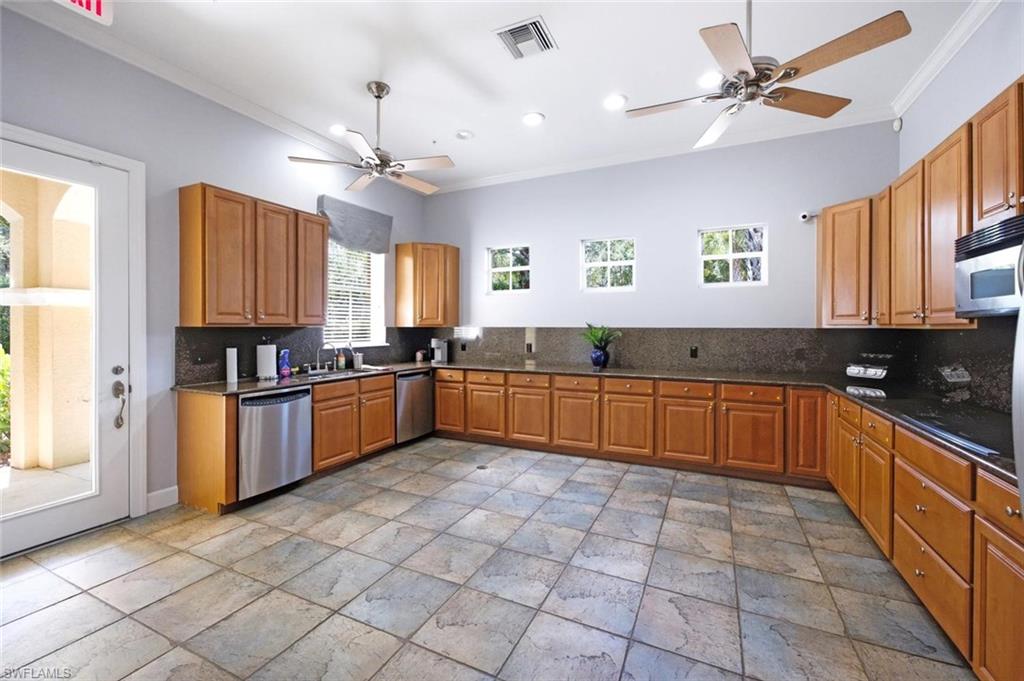 Expansive kitchen area featuring wood-finish cabinetry, dark countertops, and stainless steel appliances