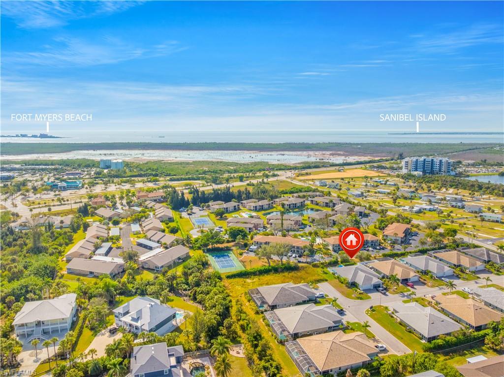 Aerial perspective featuring a residential community with mature landscaping, a tennis court, and multiple bodies of water