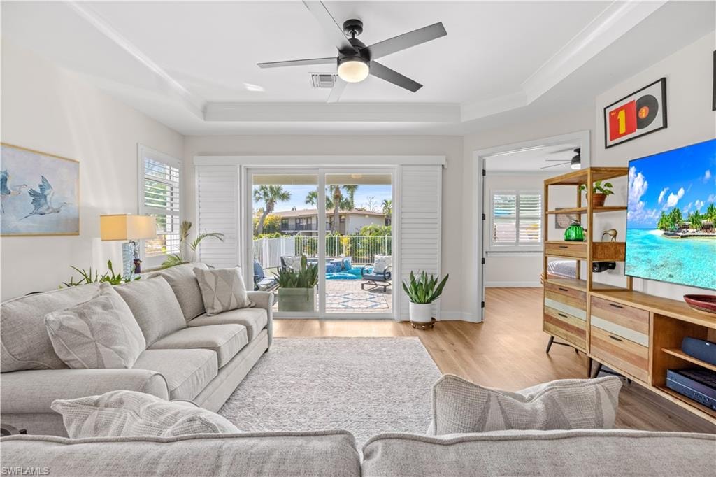 Tray ceiling with recessed lighting and a ceiling fan, wood-finish flooring, sliding glass door leading to an outdoor area with a pool, and plantation shutters on windows