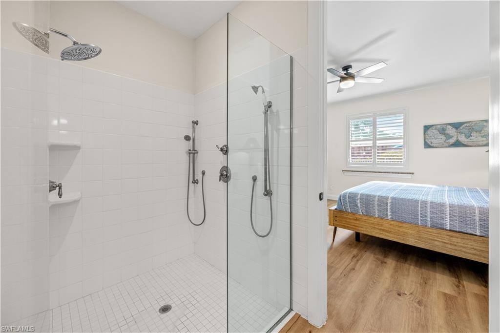 Glass-enclosed shower with white tiled walls and floor, featuring dual shower heads and a built-in shower niche