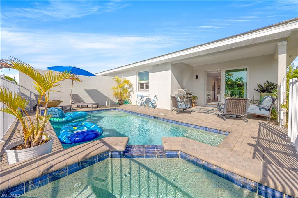 Exterior featuring a swimming pool, spa, covered patio, and privacy wall