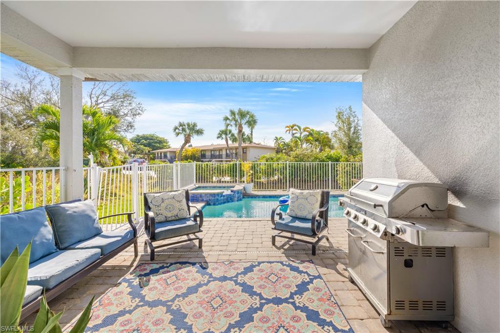 Covered patio featuring paver flooring, a white railing, and a built-in pool with an integrated spa