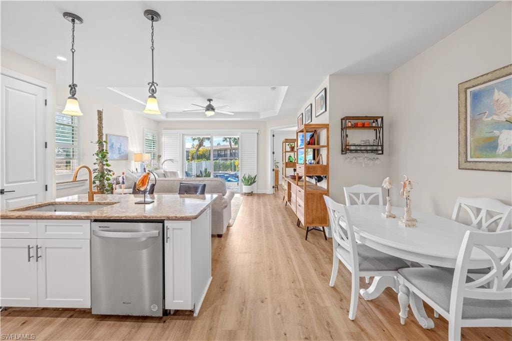 Open-concept living area with wood-finish flooring, recessed lighting, and a tray ceiling