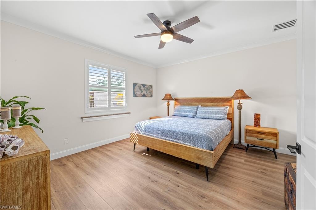 Wood-finish flooring, ceiling fan with integrated lighting, window with plantation shutters, crown molding, and white interior doors with dark hardware